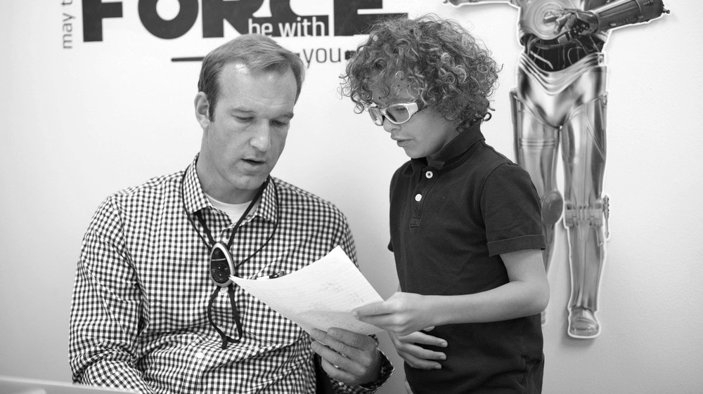 Male teacher helping young male student with assignment.